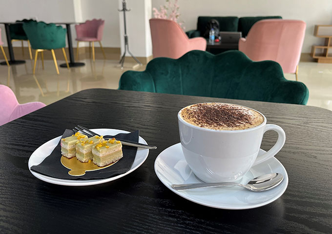 a coffee and a plate of cake on a table of Patisserie Luxe's cake shop in Poole