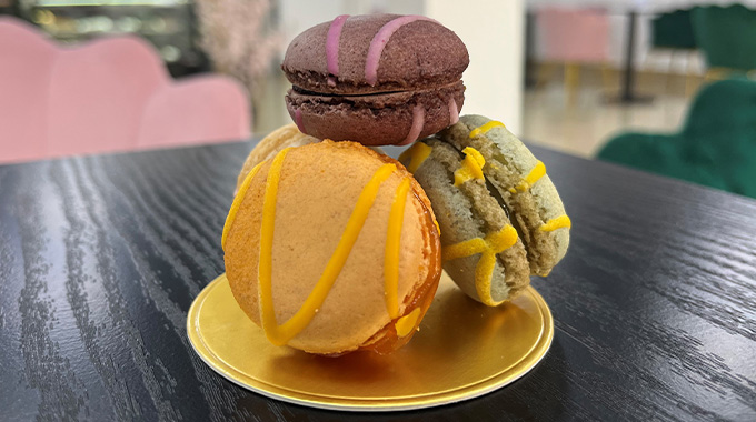 a plate of four macarons stacked elegantly on top of one another on a black table in Patisserie Luxe