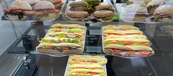 a selection of sandwiches and baguettes behind a glass cabinet at Patisserie Luxe