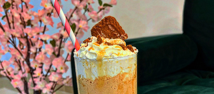 the top of a Biscoff Frappuccino with a velvet green sofa and cherry blossom branches in the background